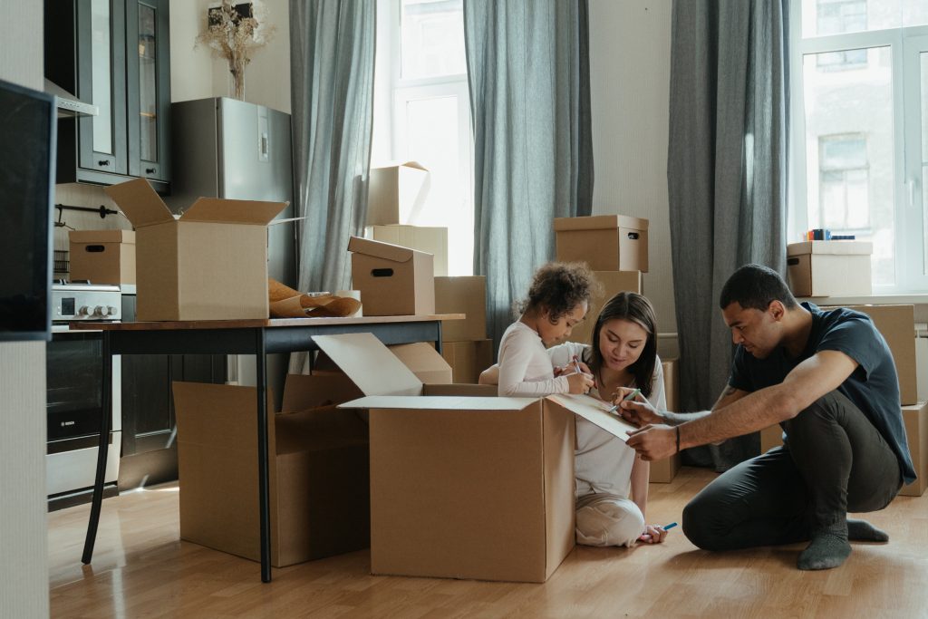 moving house checklist - family packing in house using cardboard boxes